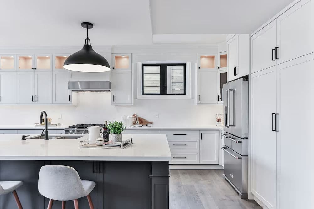 Modern white and gray kitchen featuring a sleek island, stylish pendant light, and stainless steel appliances.